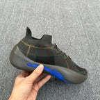 Plaid knit sneaker held in hand, with blue stripe on the side sole edge