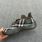 Side view sneaker in olive with black-and-white plaid upper and blue accent lines