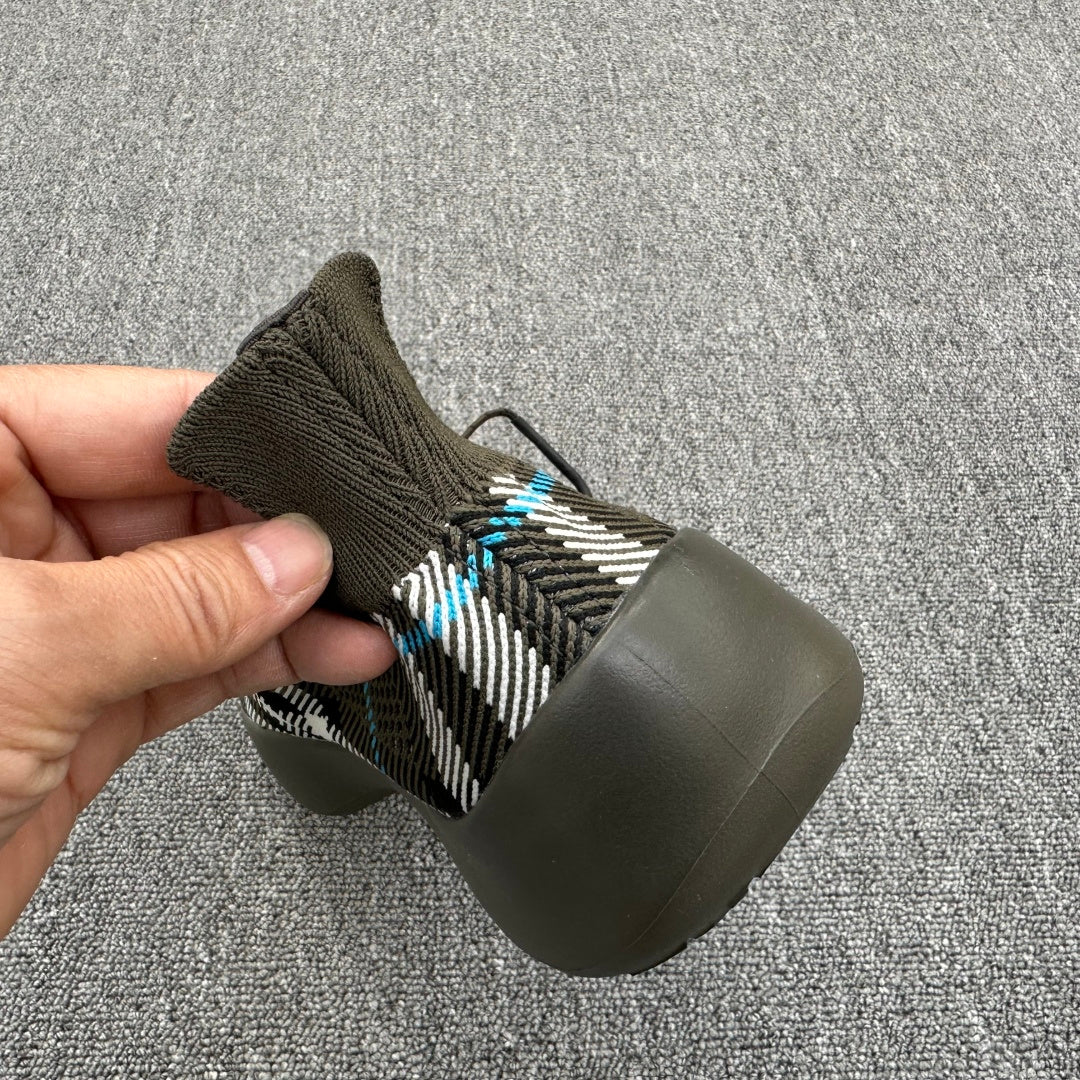 Heel view of olive sneaker with black-and-white plaid knit and blue thread accents