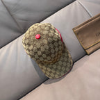Gucci baseball cap with tan GG monogram print, red button detail, and red piping.