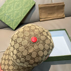 Gucci baseball cap with tan GG monogram print and red button on the crown.