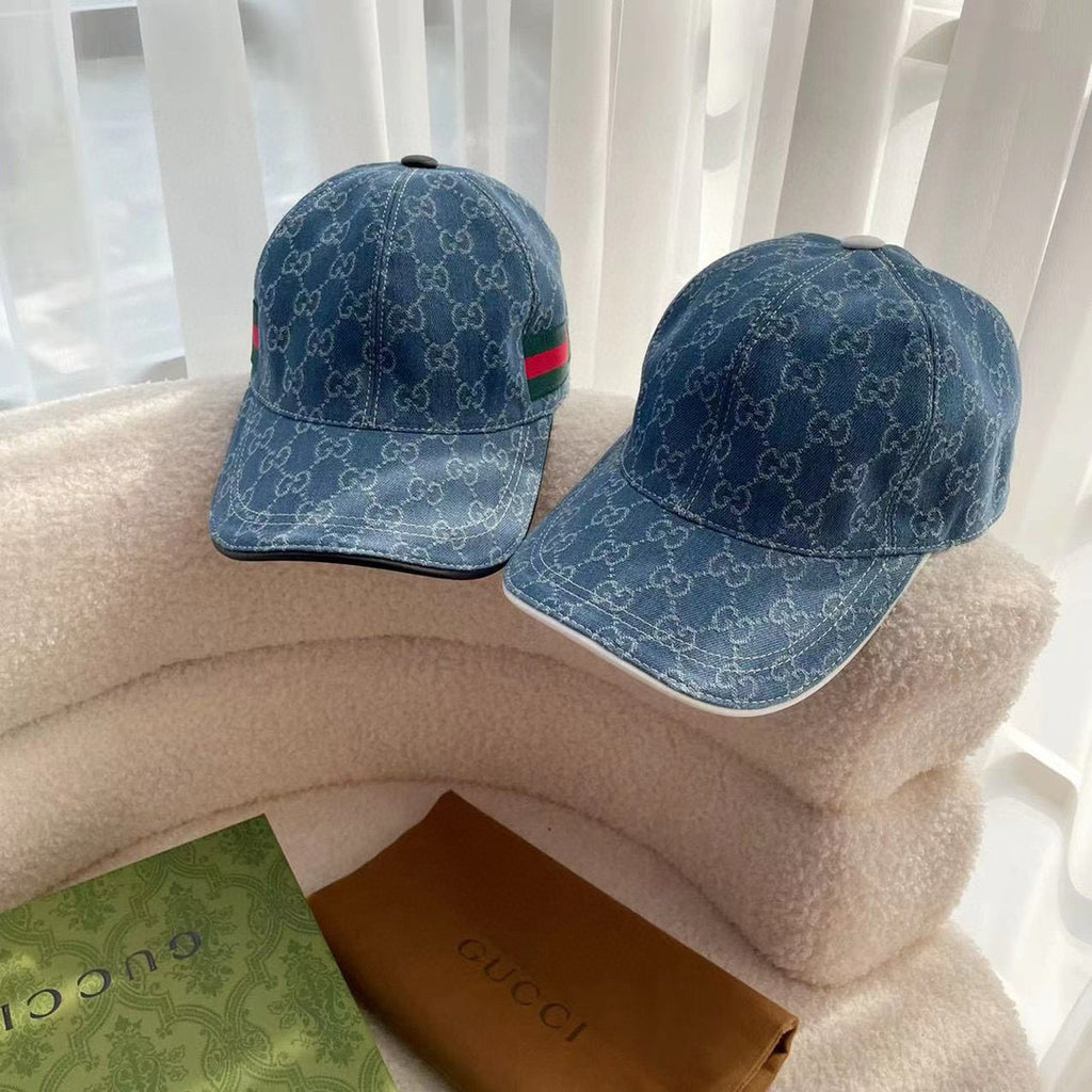 Pair of blue monogram baseball caps with green-red stripe details on the brim.