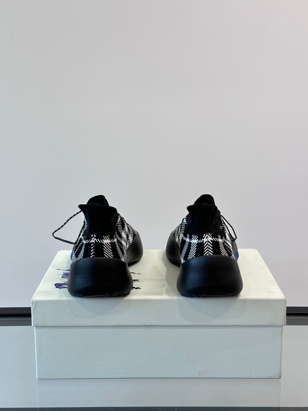 Burberry sneakers showing back heel area in black-and-white check with blue sole