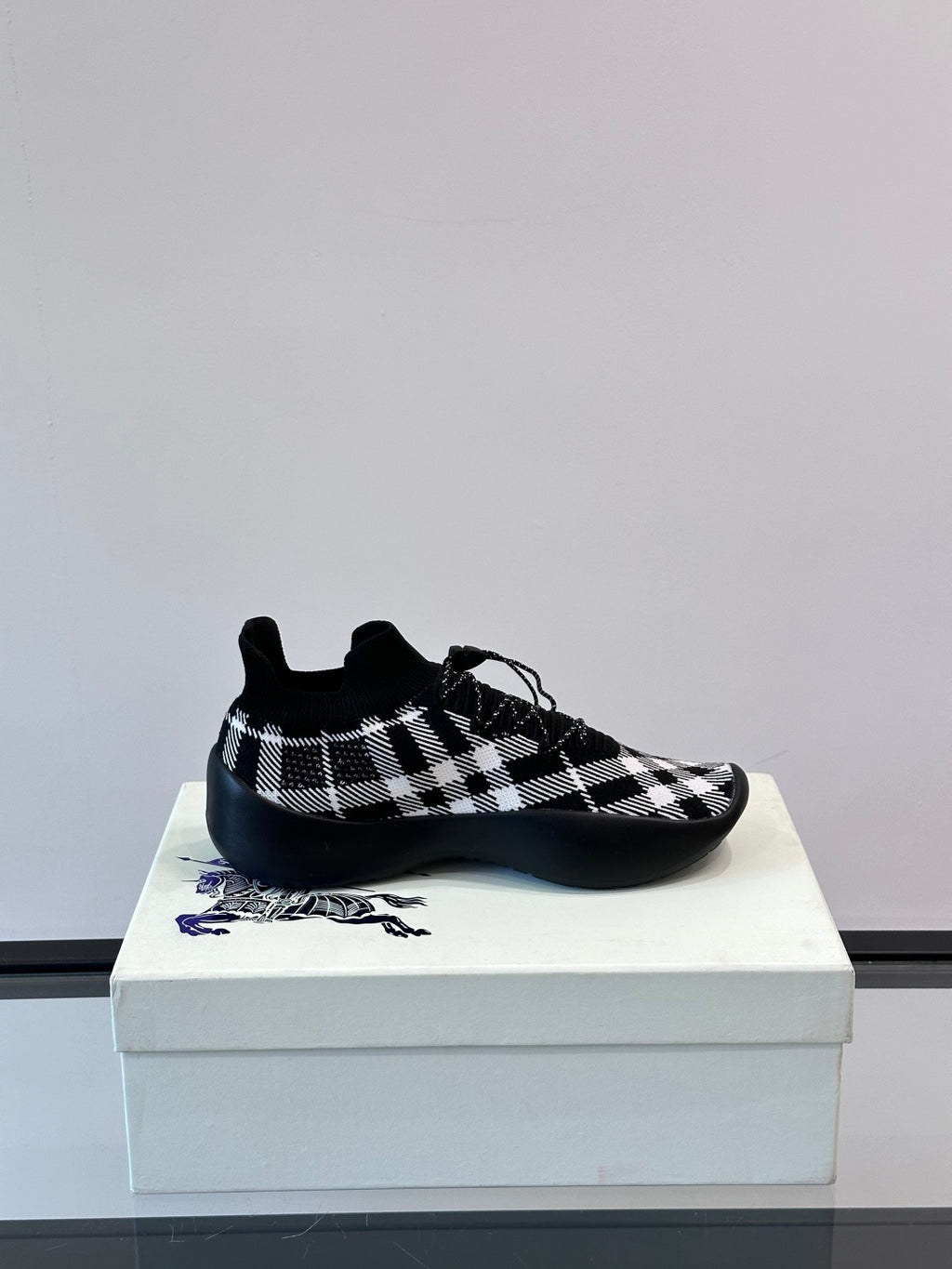 Burberry sneaker front view in black-and-white check knit with blue sole accent