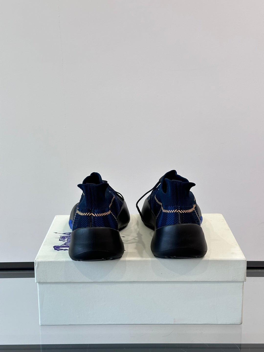 Back view of blue plaid sneakers with pull-tab heel and black rubber sole