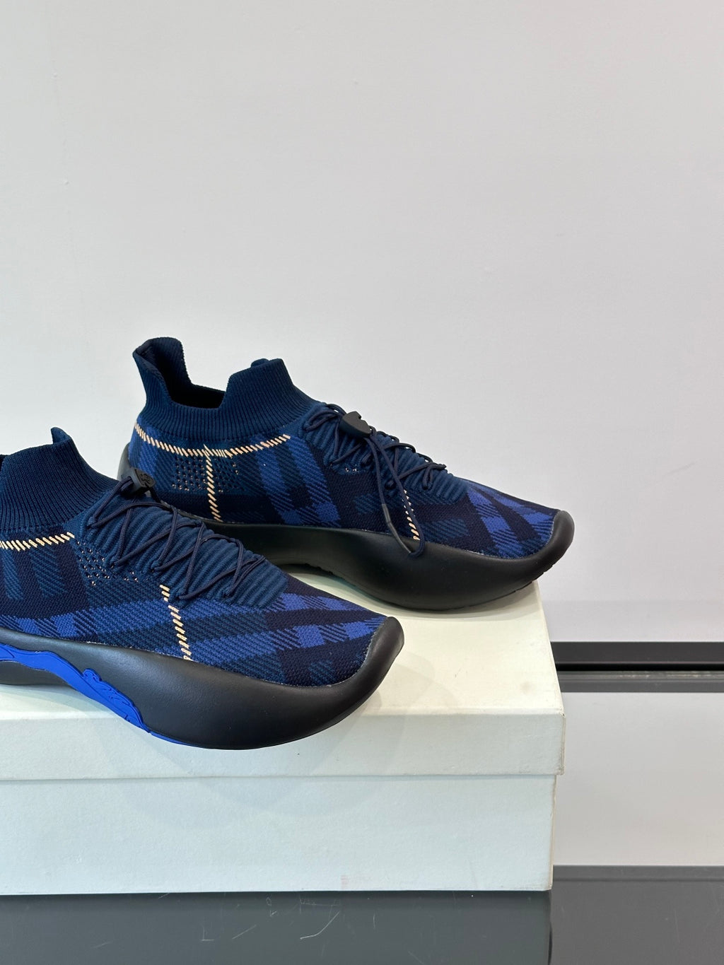 Close side view of dark blue plaid sneakers with elastic laces and blue accent on sole
