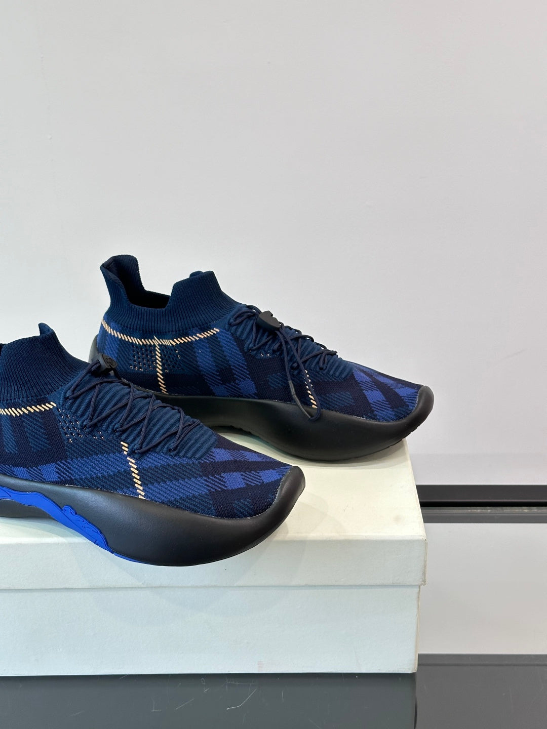 Close side view of dark blue plaid sneakers with elastic laces and blue accent on sole