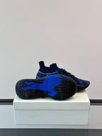 Shoe outsole view of blue and black sneakers with patterned tread and blue sole insert
