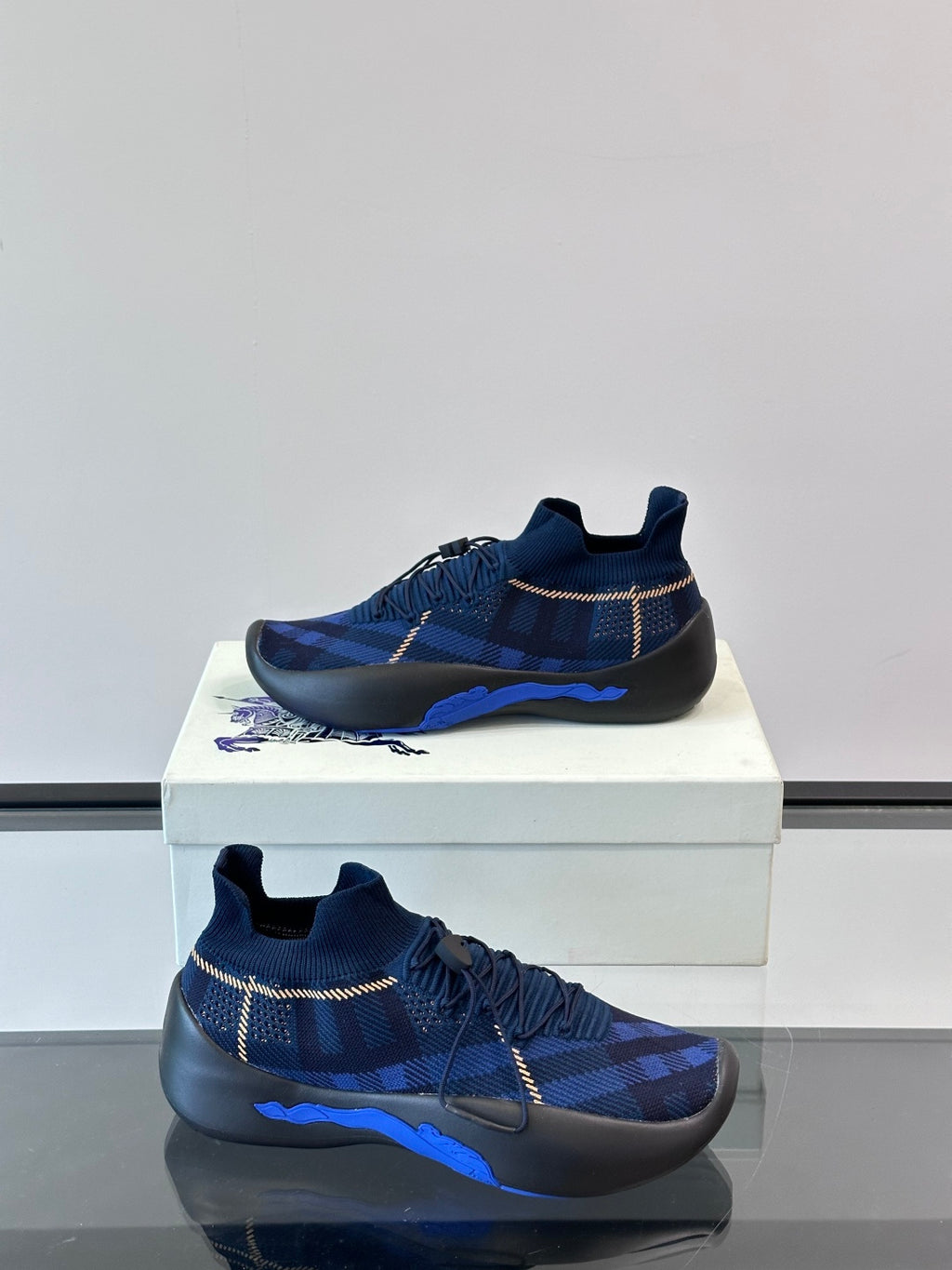 Side view of navy plaid sneakers with pull-tab collar, elastic laces, and blue outsole stripe