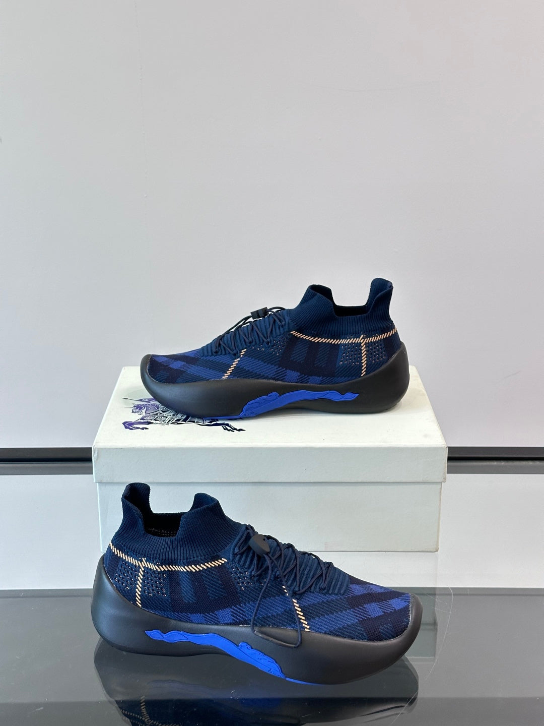 Side view of navy plaid sneakers with pull-tab collar, elastic laces, and blue outsole stripe