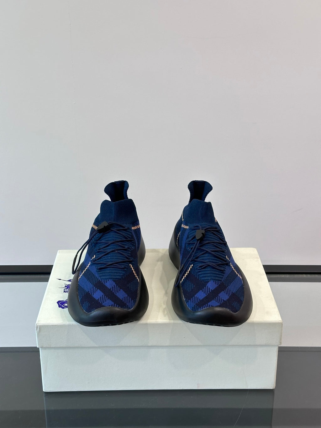 Pair of dark blue plaid sneakers with pull-tab collar, laces, and blue-trimmed sole