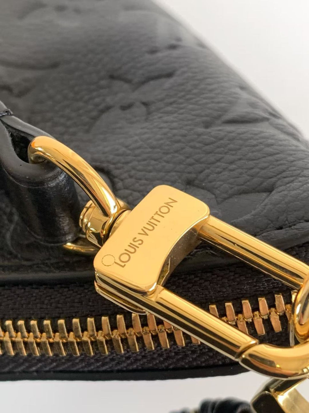 Louis Vuitton black bag close-up of gold zipper pull and embossed leather texture