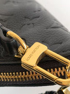 Louis Vuitton black bag close-up of gold zipper pull and embossed leather texture