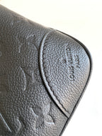 Louis Vuitton black leather bag corner close-up with embossed logo on flap