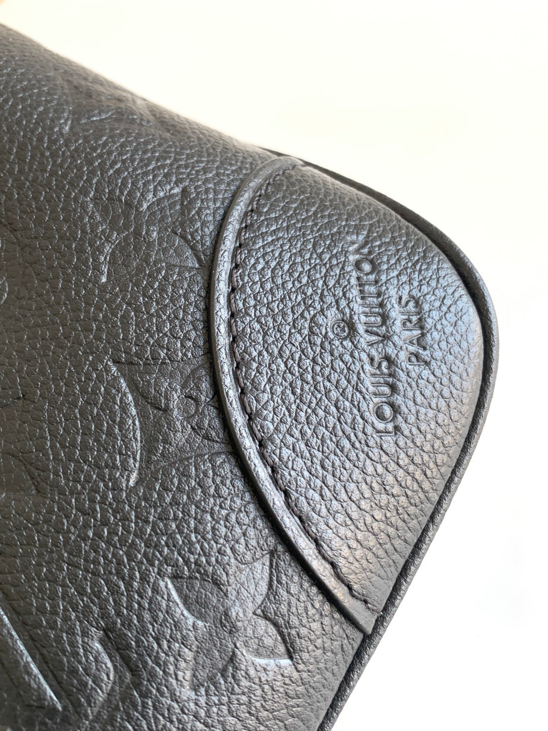 Louis Vuitton black leather bag corner close-up with embossed logo on flap
