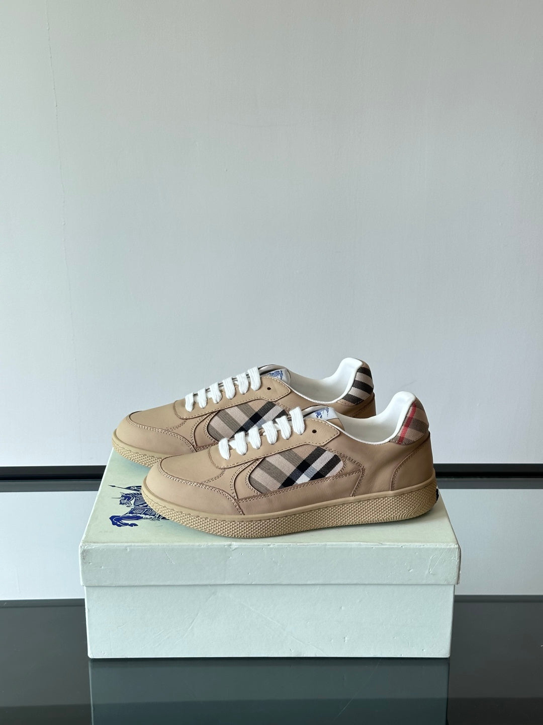Beige low-top sneakers with white laces and Burberry check strap across sides