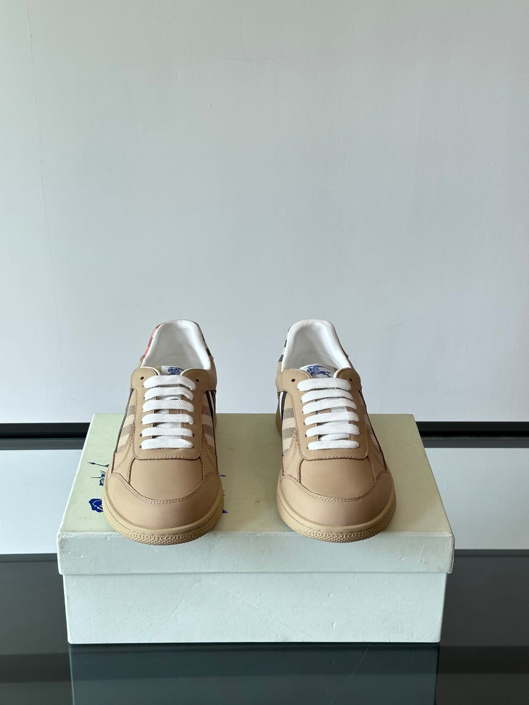 Beige low-top sneakers, white laces, rear view with check heel accents