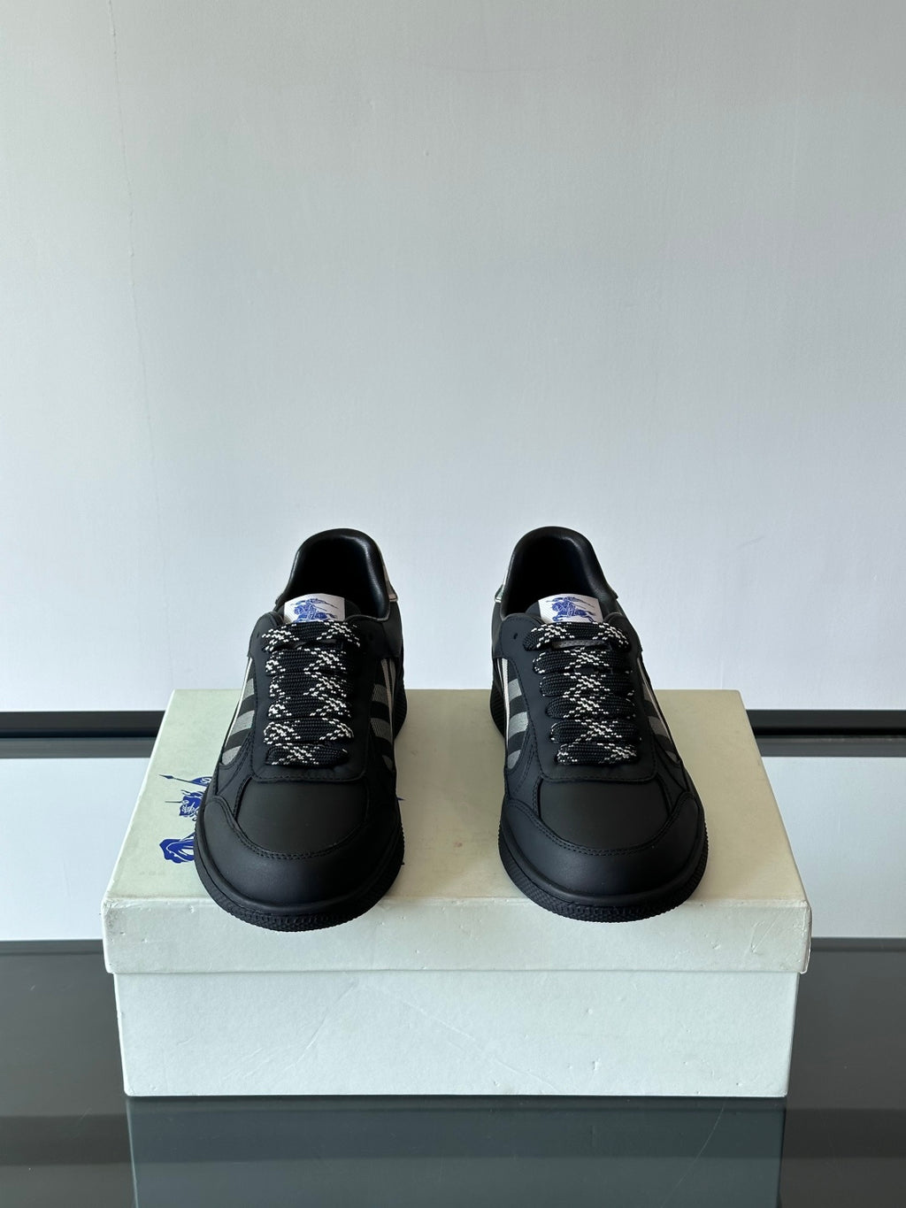 Pair of black low-top lace-up sneakers with plaid patterned tongue detail