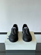 Pair of black low-top lace-up sneakers with plaid patterned tongue detail