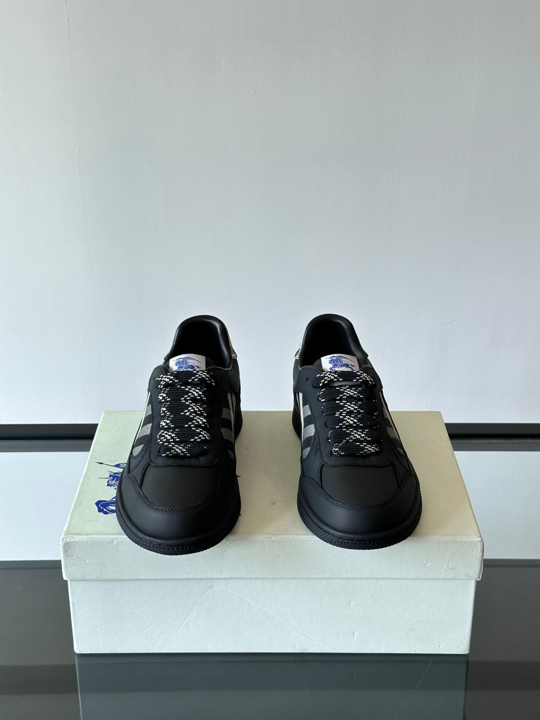 Pair of black low-top lace-up sneakers with plaid patterned tongue detail