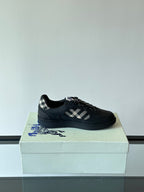 Black low-top sneaker on a box with plaid panel and black textured lace-up
