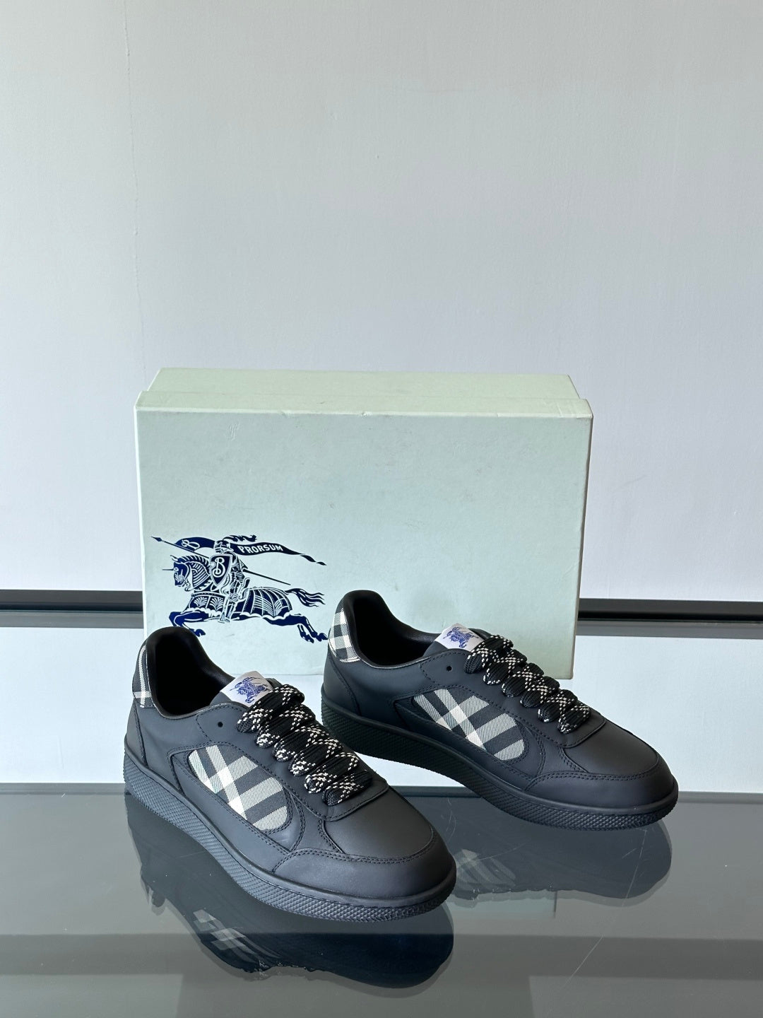 Pair of black low-top sneakers with plaid panel and black braided lace detail