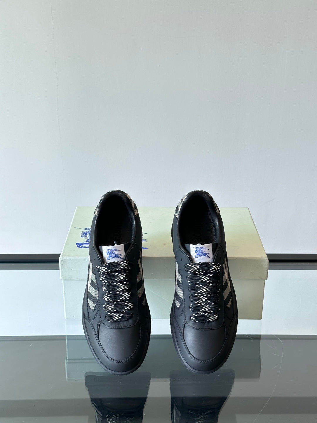 Pair of black low-top sneakers from front view with plaid lace-panel details