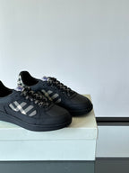 Close view of black low-top sneakers with plaid panel and lace-up detail