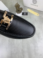 Close-up of black textured leather loafer with gold-tone buckle strap