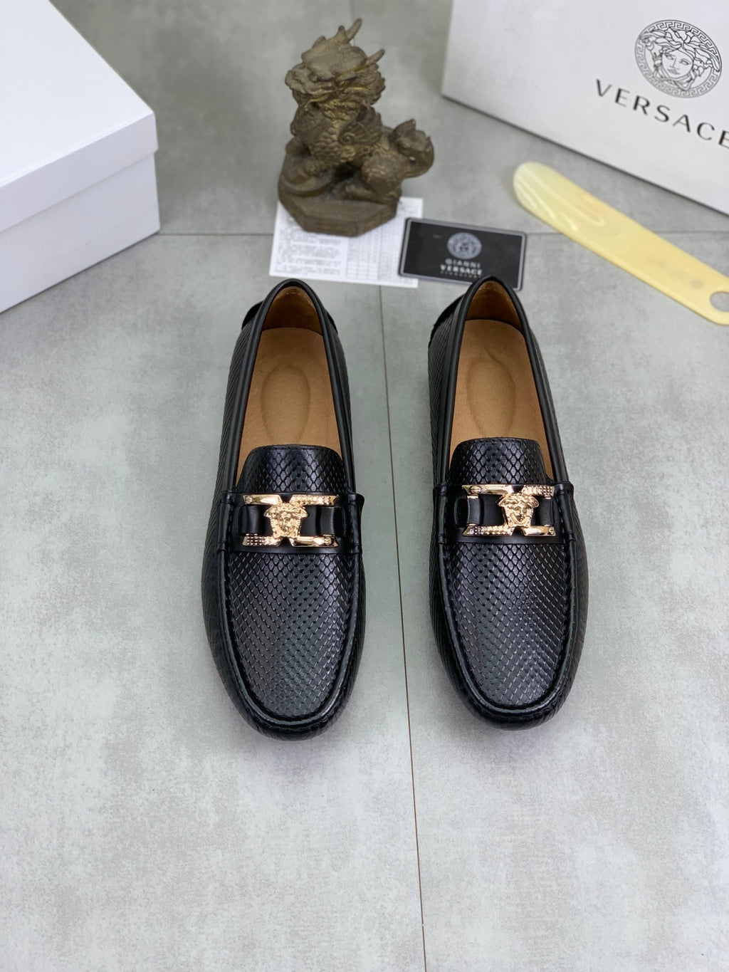 Pair of black leather loafers with gold-tone buckle strap and textured upper