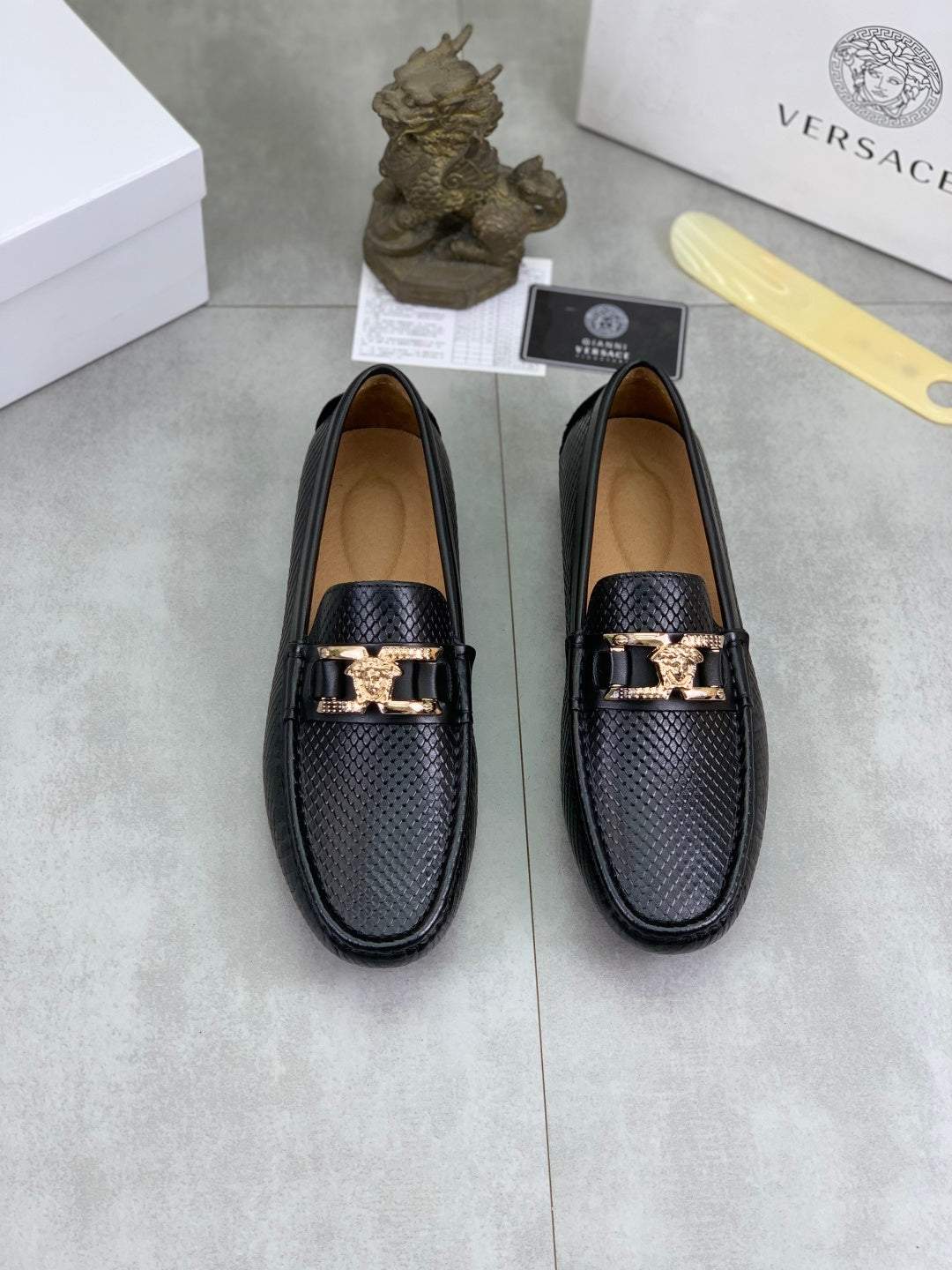 Pair of black leather loafers with gold-tone buckle strap and textured upper