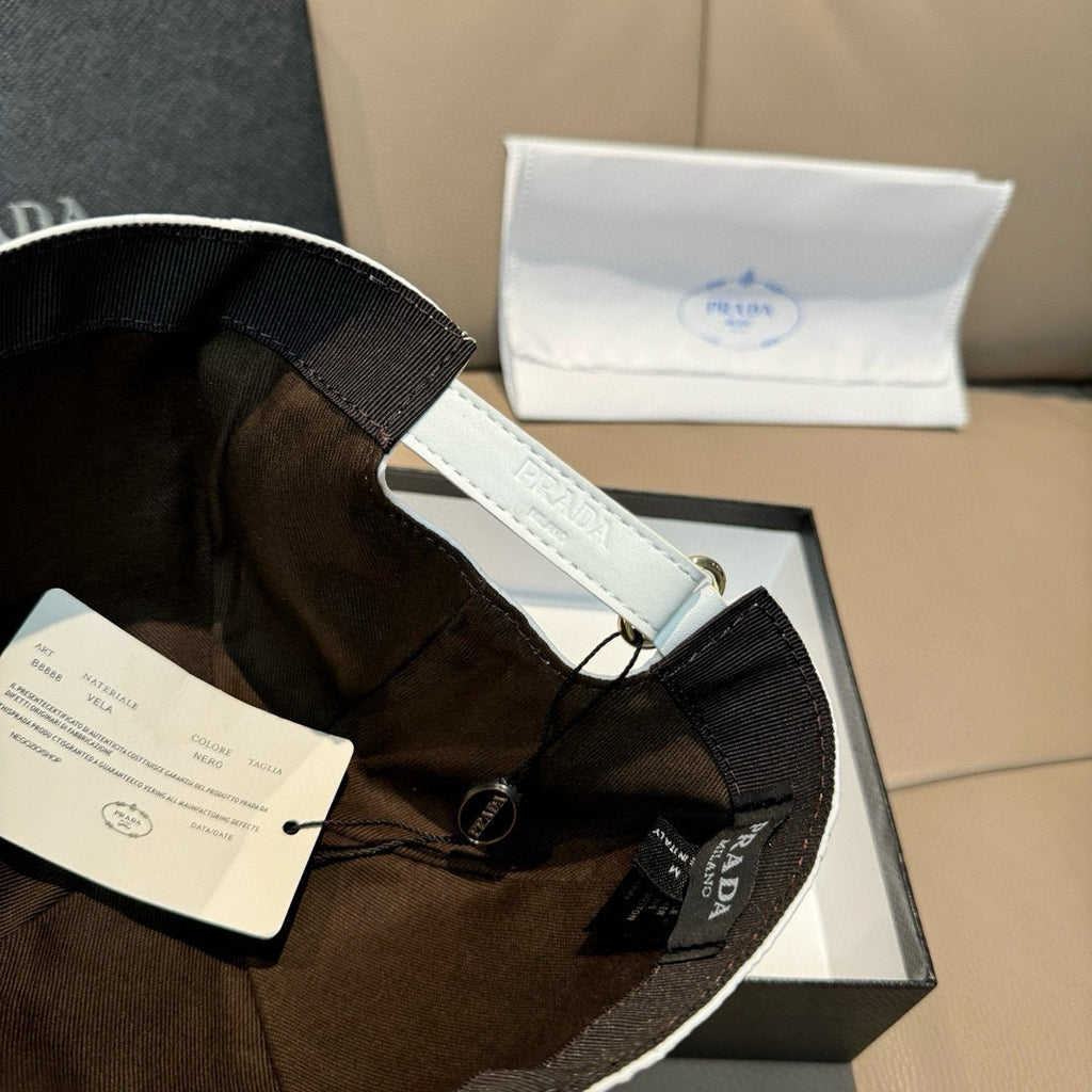 Prada cap in dark brown fabric with black webbed strap and round logo tag