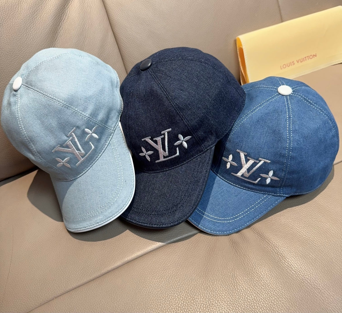 Set of three Louis Vuitton denim caps: light blue, navy, and medium blue with LV logos.