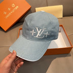 Louis Vuitton denim baseball cap in light blue with LV logo, held in a hand.