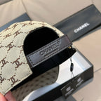 Chanel cap close-up: beige monogram panel with Chanel-branded dark strap trim