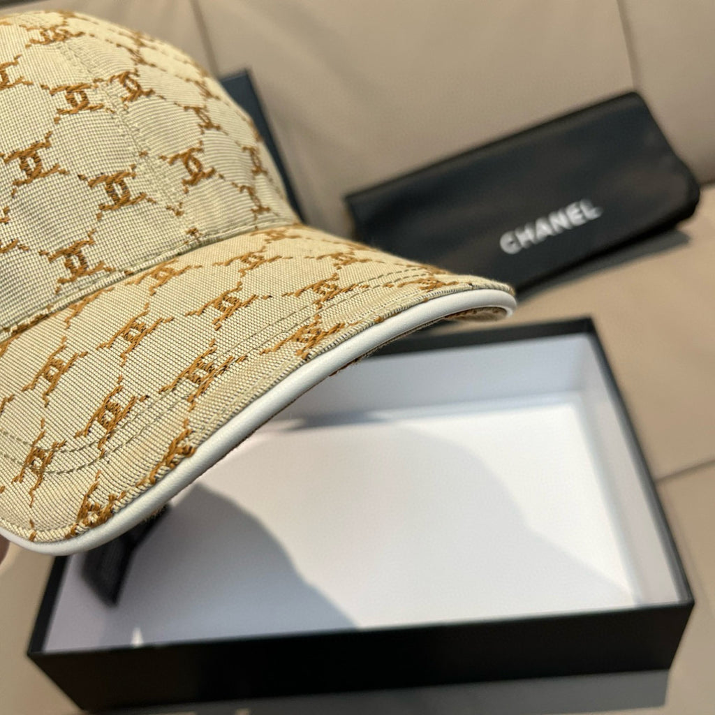 Close-up of beige monogram baseball cap brim with stitched edge; curved visor
