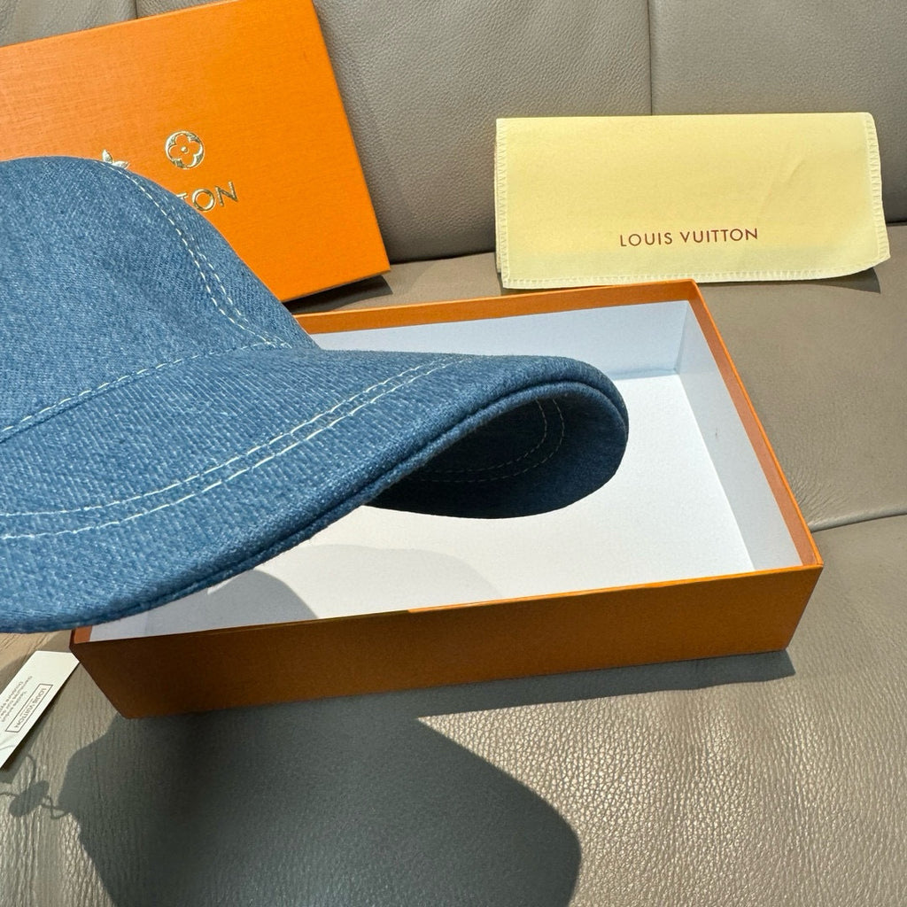 Blue denim baseball cap side view with curved brim and top stitching.