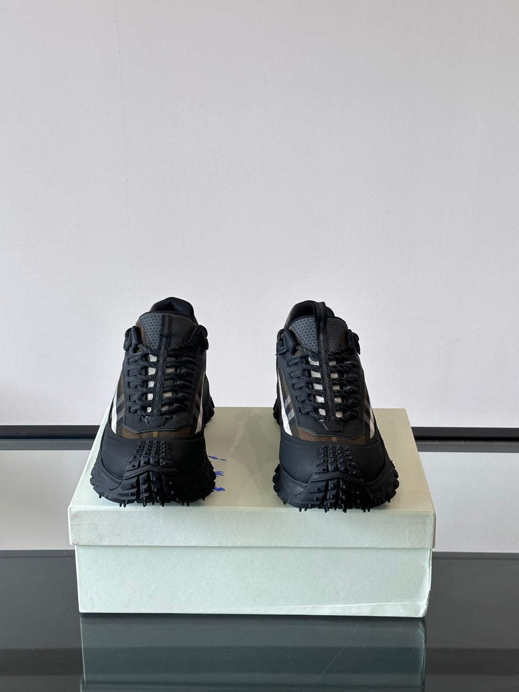 Pair of black lace-up chunky sneakers on the box with deep lug soles