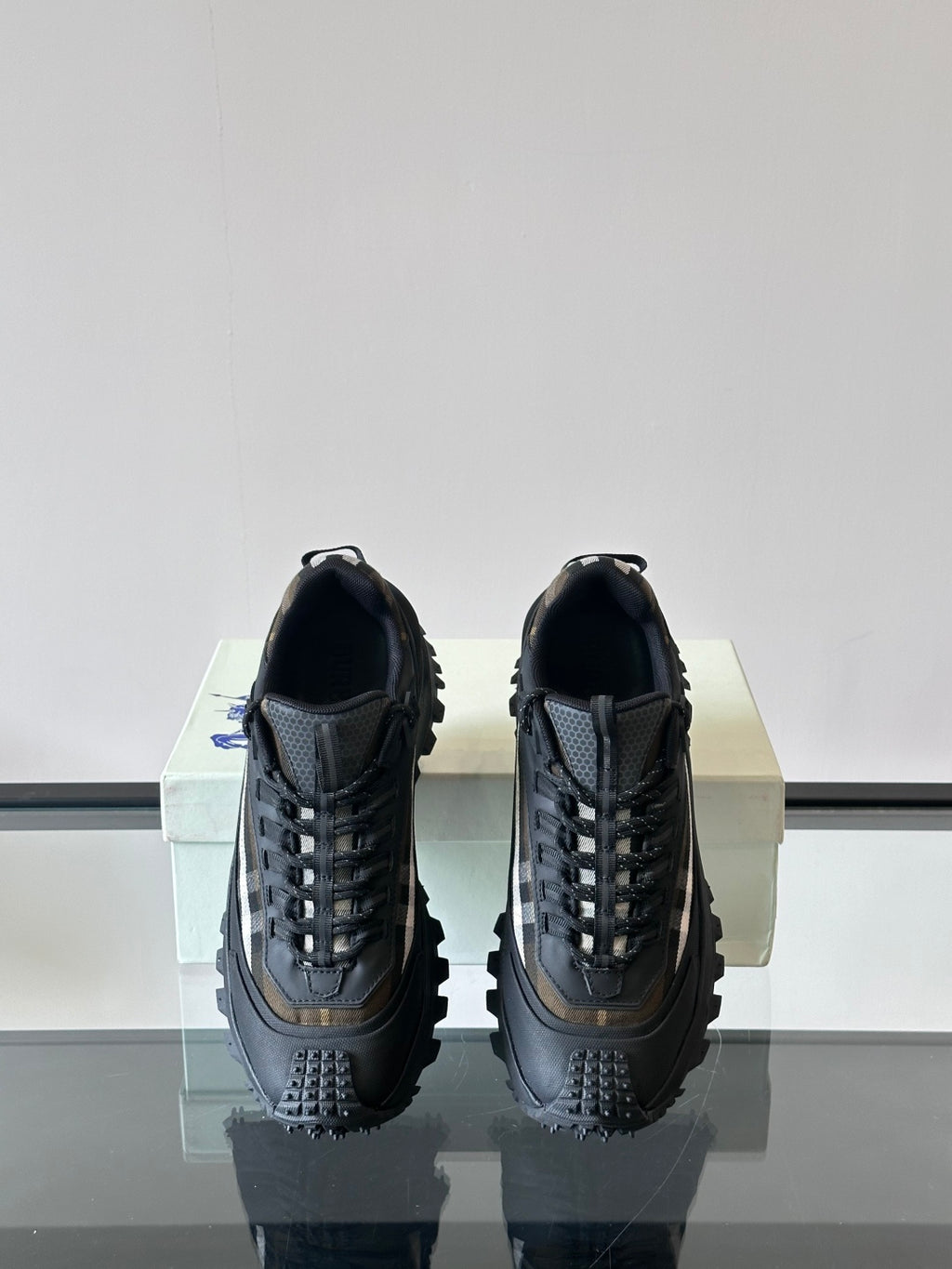 Black lace-up chunky sneakers shown from the heels with textured panel detailing