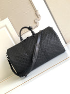 Black monogram duffel bag with dual top handles and long shoulder strap