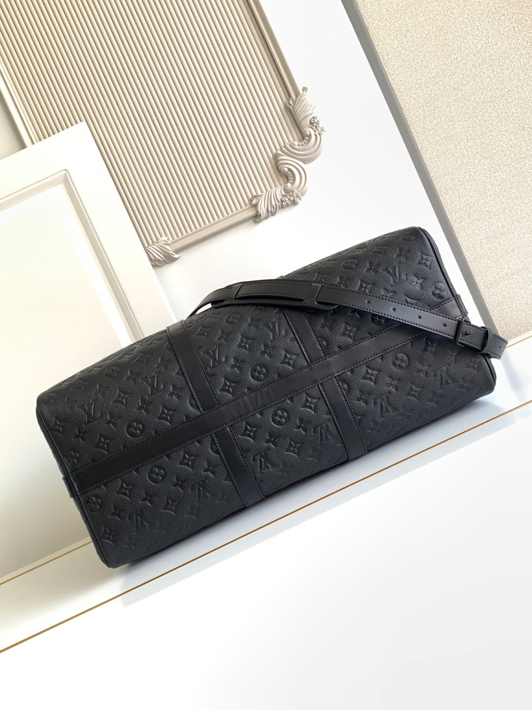 Black monogram duffel bag lying flat with zip top and shoulder strap