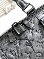 Black monogram duffel bag zipper pulls with metal charms and embossed pattern