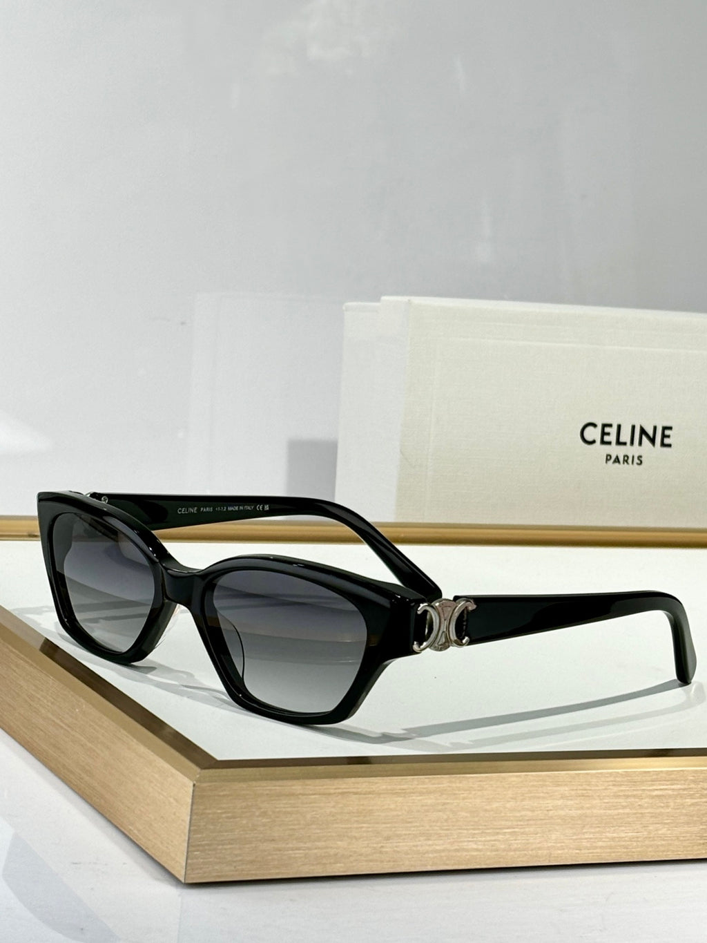 Black cat-eye eyeglasses with dark lenses and gold C emblem on the bridge