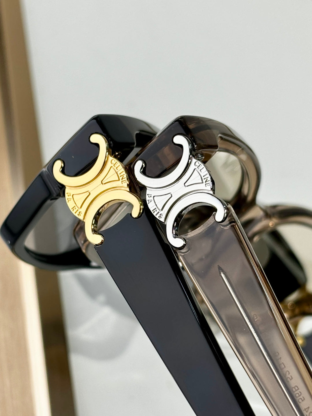 Close-up of black eyeglasses bridge with gold C emblem and metal arms