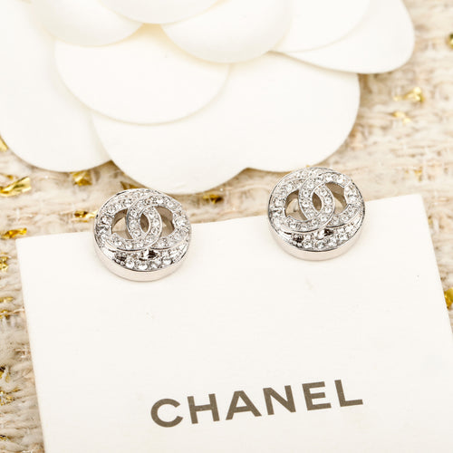 Silver CHANEL logo stud earrings on a white display card