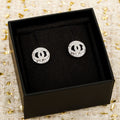 Pair of silver CHANEL logo stud earrings in a black presentation box