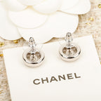 Silver CHANEL logo stud earrings shown from the front on a card