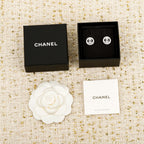 CHANEL stud earrings with black and white gift boxes and a white flower accessory