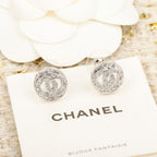 Silver CHANEL logo stud earrings on a branded display card