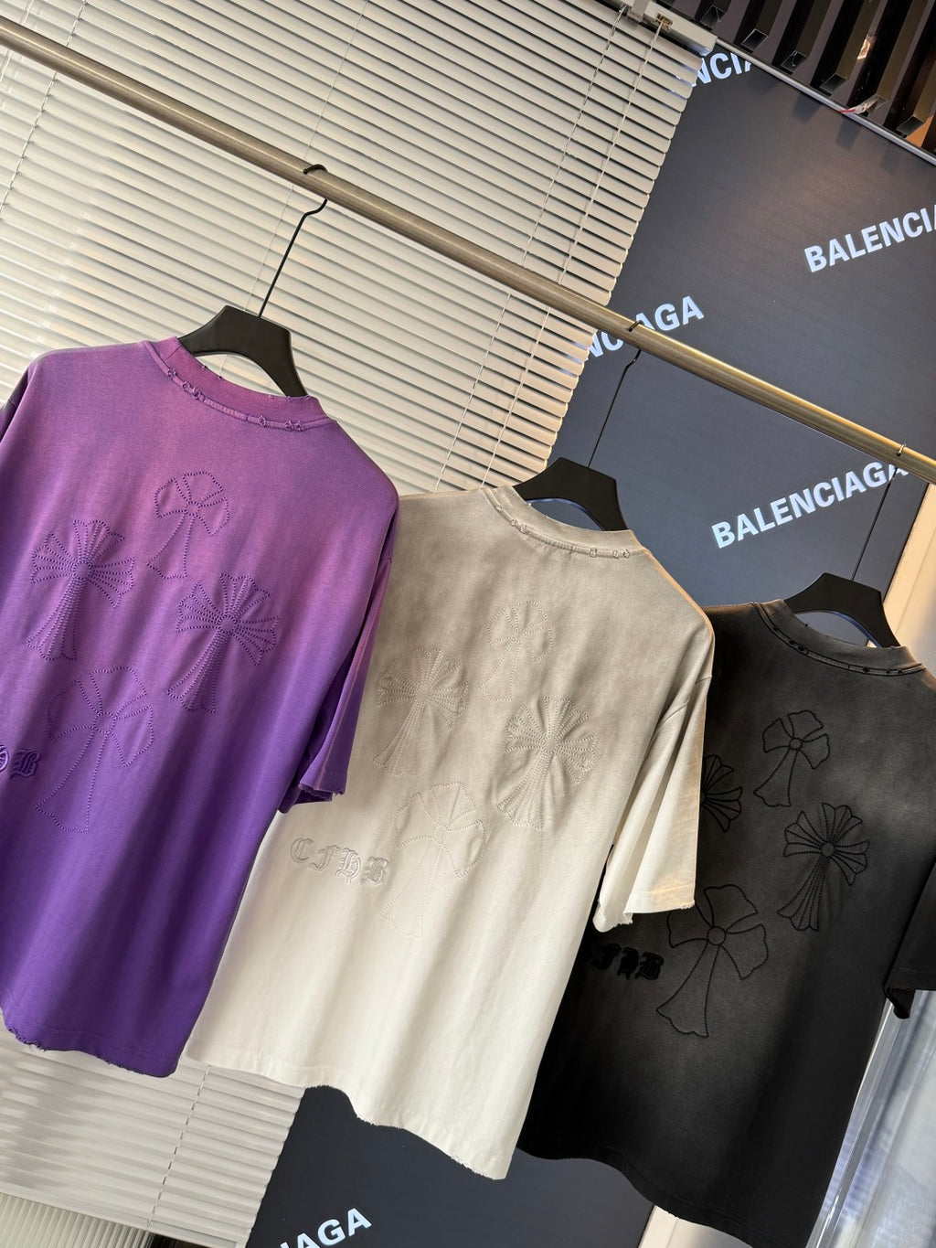 Short-sleeve T-shirts in purple, cream, and dark gray, featuring embroidered flower graphics.